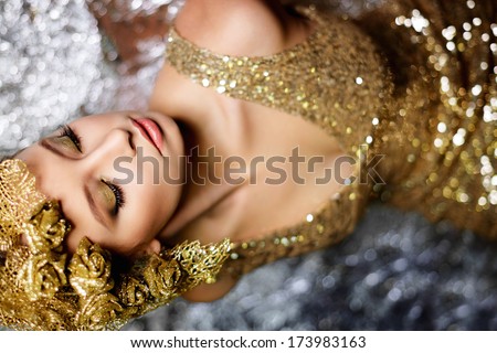 sexy woman with gold roses and leaves in gold dress on silver background