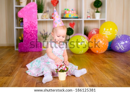 Cute funny little kid in first birthday with colored balloons