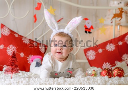 little funny girl near the Christmas  illuminations  at home on the bed in rabbit ears