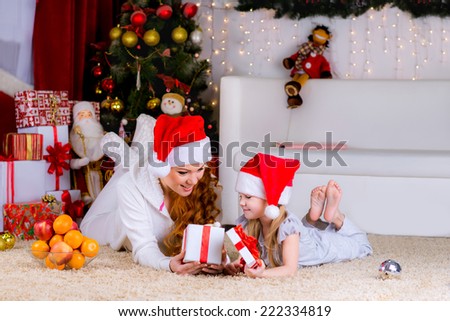 beautiful family mother and her baby on the floor near the Christmas tree on Christmas Eve open box with a gift
