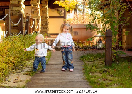 brother and sister happy together walk in autumn park in sunny weather