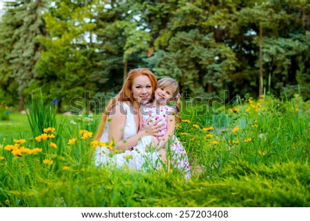 mother and daughter in the park on the grass among flowers spring summer Mom and child in the park on the grass among flowers happily play together spring summer