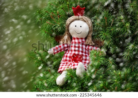 Greeting card with handmade angel on christmas tree under the snow flakes