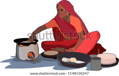 Indian village woman cooking food with traditional way of baking chapati on wood fire stove (chulha)