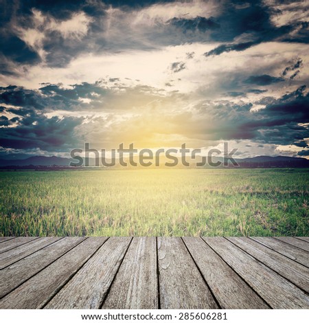 vintage photo of storm clouds and field meadow with wood table