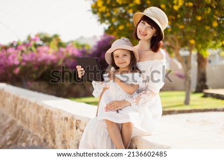 Pretty young mother and cute little daughter using a tablet computer on a sunny day while relaxing on clean fresh morning air and reading e book on touch pad. Concept of summer vacation. Foto stock © 