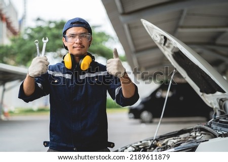 Confident Asian auto mechanic holds a wrench and inspects the maintenance vehicle as per customer's claim in the garage. Auto repair service. Engine maintenance and repair concept. Stok fotoğraf © 