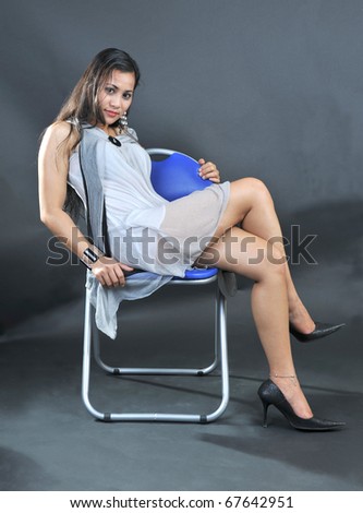 Portrait of beautiful young woman sitting on chair isolated over black background