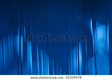 blue curtain on stage lighted with spotlight rays
