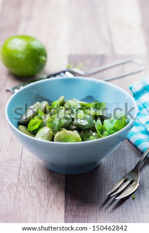 Bowl of green boiled broad beans, salad with broad beans, garlic and lime