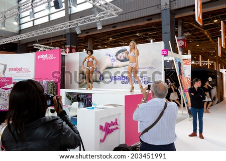 PARIS, FRANCE - JULY 5, 2014: People photograph models at Mode City, a swimwear and lingerie tradeshow where over 20,000 buyers meet 500 exhibitors from 35 different countries.