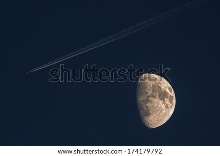 Night sky with the Moon, airplane and its contrail.