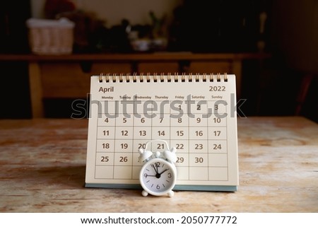 April 2022 calendar and little vintage white alarm clock on a wooden table Foto d'archivio © 