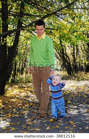 daddy and his little son walking through the park in autumn