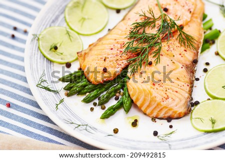 salmon fillet with asparagus in a dish with a blue border and a blue stripe placemat