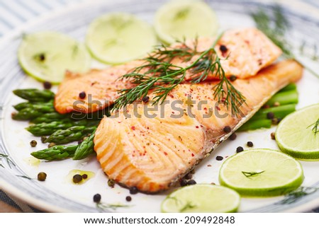 salmon fillet with asparagus in a dish with a blue border and a blue stripe placemat