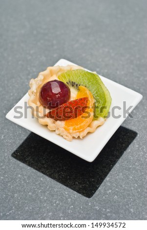 bite size of fruit tart on small white plate on black table