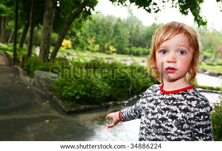child in rain soaked with water. wet kid caught in storm in park or garden