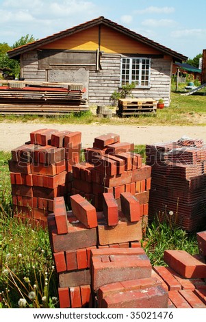 building site with pile of bricks and materials in front of timber building