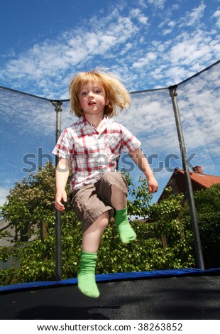 child jumping on trampoline. toddler in garden is active playing and jump
