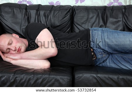 man tired and sleeping on sofa. male relaxing or napping on leather couch