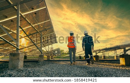 Low angle view of technician walks with investor through field of solar panels, Alternative energy to conserve the world's energy, Photovoltaic module idea for clean energy production.