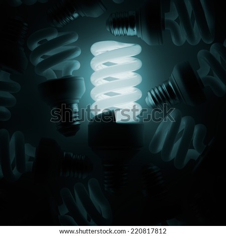 Glowing light bulb among other ones in the darkness