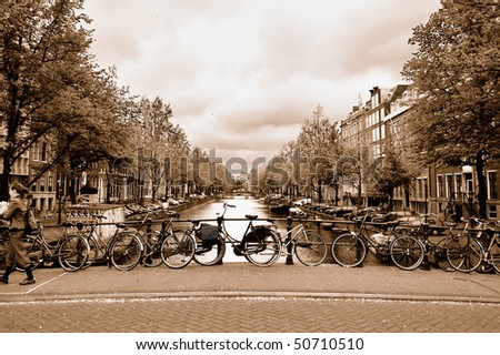 Typical view of the Amsterdam center with bicycles on a bridge across a canal in overcast spring day. Sepia toned image.