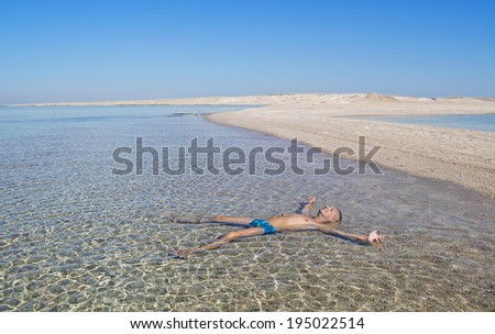 Leisure, pleasure. Egypt, Red Sea. Sand, deserted island. A man sunbathes lying in the water.