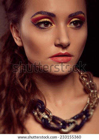 Portrait of young beautiful brown-eyed  woman with fashion hairstyle and orange yellow makeup. Fashion model shooting. Gold blue jewelry.