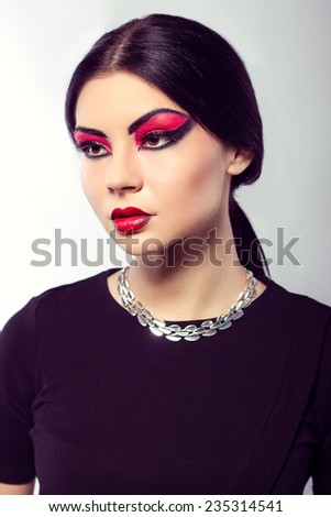 Close up  portrait of young beautiful  brown-eyed  woman with long black hair on white background. Arab woman. Scarlet makeup and black arrows. Fashion model shooting. Silver jewelry.