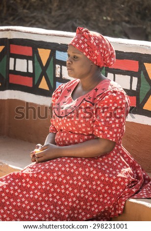 South Africa, Gauteng, Lesedi Cultural Village (unique center of African culture) - 04 July, 2015 . Ndebele woman Bantu in traditional handmade ethnic red white dress and hat.