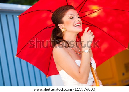beautiful woman laughing with perfect skin wearing professional make-up holding a red umbrella