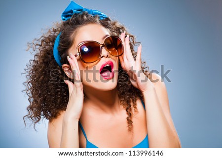 cute pin up girl with curly hair and perfect teeth on blue background