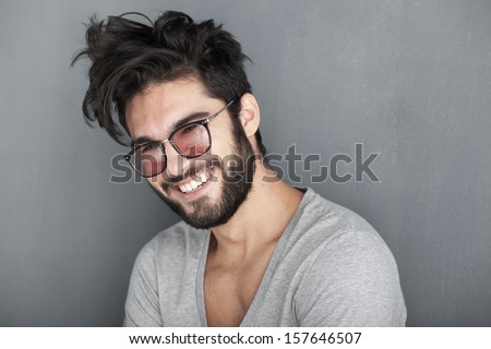 sexy man with beard smiling big against wall