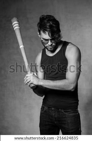 sexy fashion man model with a baseball bat posing dramatic against grunge wall
