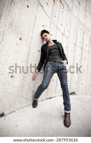 Attractive man dressed in jeans and boots in a grungy scenery