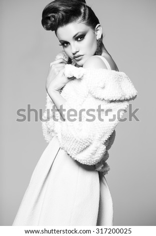 beautiful woman with long legs in white dress, fur and high-heels posing in the studio