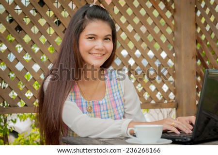 A shot of a beautiful asian woman drinking coffee in the garden with laptop