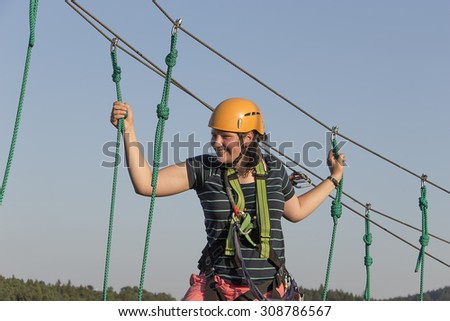 Teenage girl climbing in adventure park.