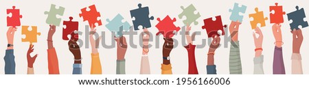  Group of multi-ethnic business people with raised arms holding a piece of jigsaw. Colleagues of diverse races and culture. Cooperate and collaborate. Concept of teamwork and success