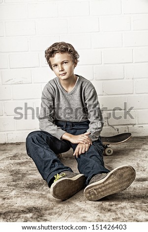 A Teenage boy, sitting on his skateboard looking straight into the camera. Picture Processed (See also natural version)