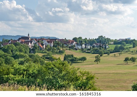Village in Southern Germany, fields and meadows with Castle Hohenzollern in the background
