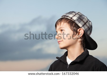 Charming Teenage Boy wearing a black sweater standing outside.