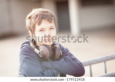 Young boy outside in urban environment with headphones in vintage look