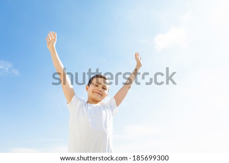Happy Boy outside, both arms up in the air. Blue sky.