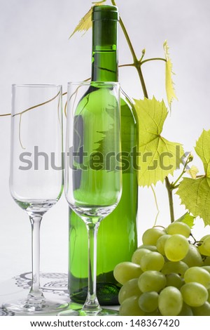 White wine bottle presented with wine glasses on a bright background