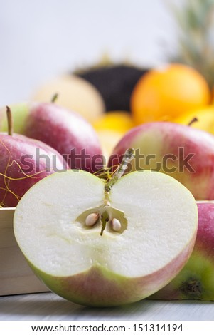 Close up photo of edible fruits - a apples with other full colors fruits in the background on a solid  bright blue wooden table