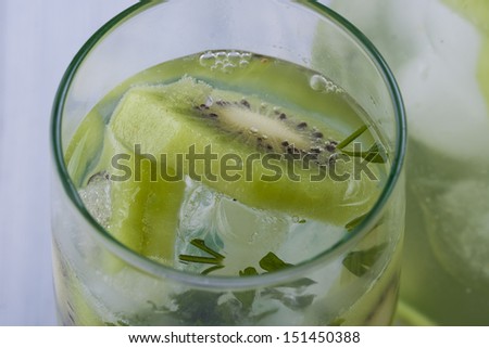 Fresh fruit and water drink with a green kiwi slices, mint herb and ice cubes.