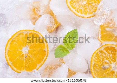 Composition of fresh orange fruits slices with ice cubes and mint herb leaf.